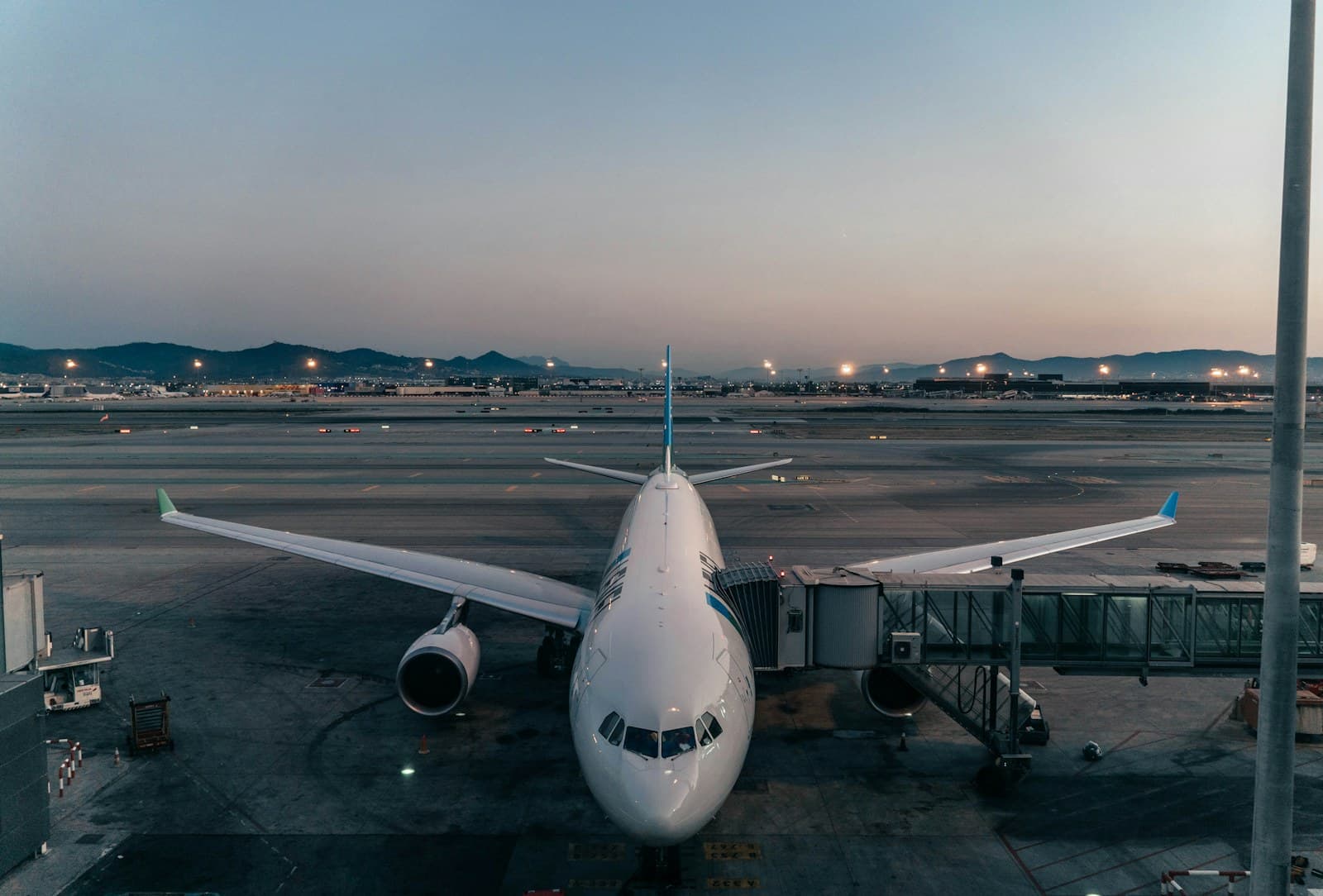 Aircraft parked at an airport gate at dusk with ground equipment alongside